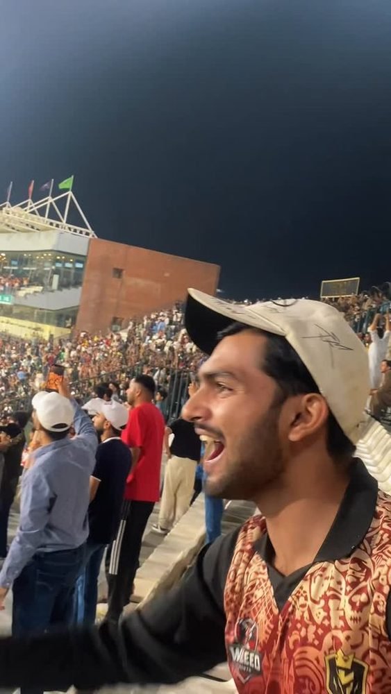 Waleed cheering in a stadium crowd at night