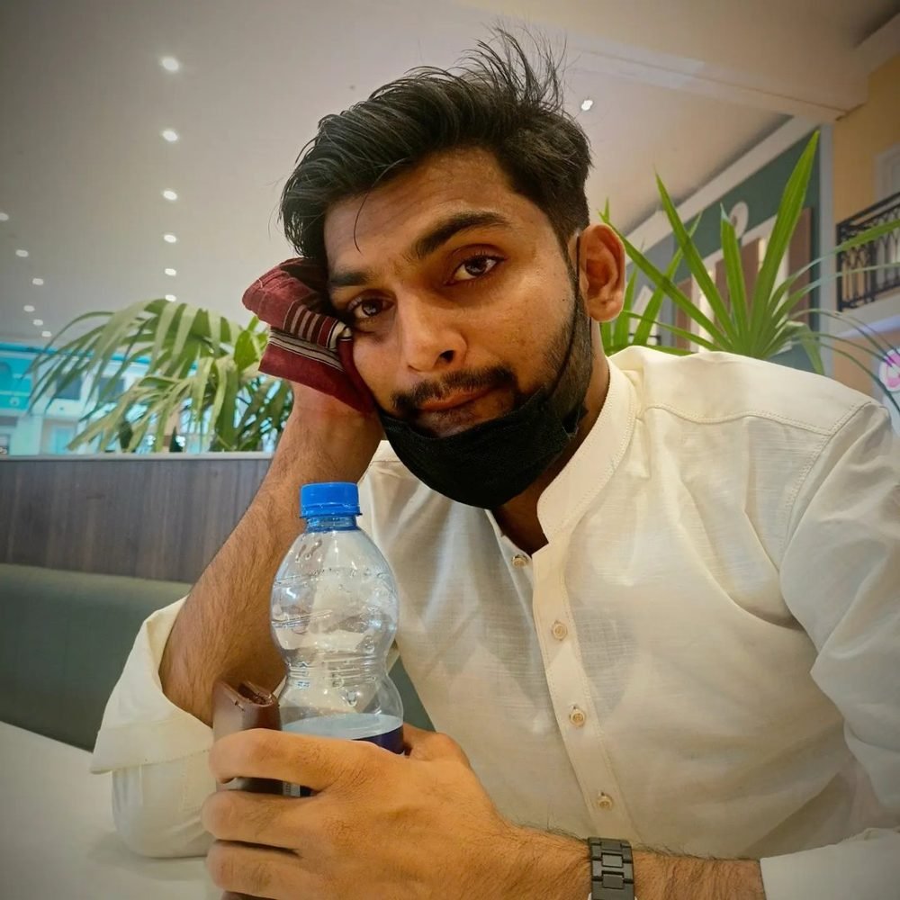 Waleed sitting in a café with a water bottle, resting his head on his hand