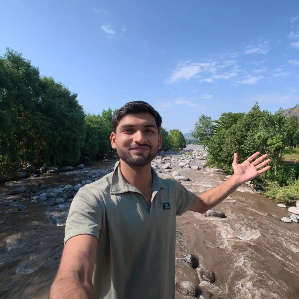 Waleed with his arms out beside a mountain river in northern Pakistan