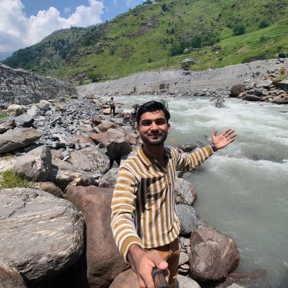 Waleed waving from the rocks beside a fast river in Kaghan valley